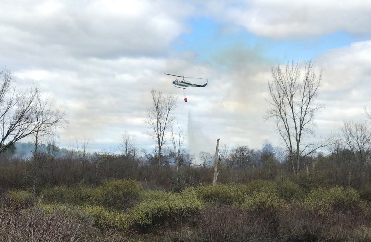 A Maine Forest Service helicopter drops water on a fire burning Tuesday afternoon on about 10 acres along Intervale Road in New Gloucester.