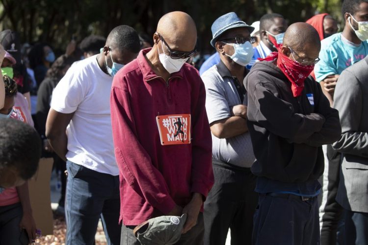 People pray during a rally to protest the shooting of Ahmaud Arbery, an unarmed black man, in Brunswick Ga. Georgia's attorney general on Sunday asked the U.S. Department of Justice to investigate the handling of the killing of Arbery, who authorities say died at the hands of two white men as he ran through a neighborhood. 