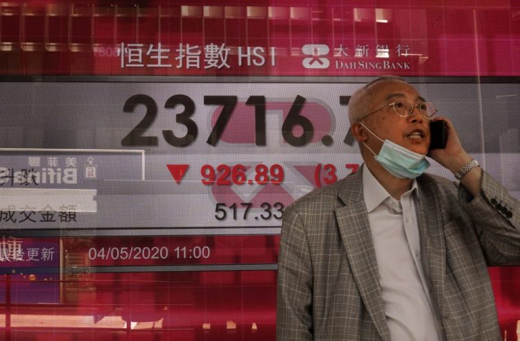 A man wearing a face mask walks past a bank electronic board showing the Hong Kong share index at the Hong Kong Stock Exchange on Monday.