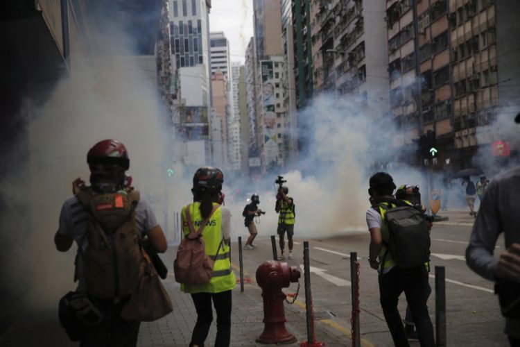 Members of the media take cover as police fire tear gas during a protest against Beijing's national security legislation in Causeway Bay in Hong Kong on Sunday. Hong Kong police fired tear gas in a popular shopping district as hundreds took to the streets to march against China's proposed tough national security legislation for the city. 