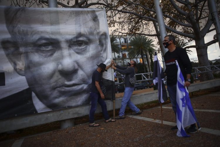 Protesters hang a banner showing Israeli Prime Minister Benjamin Netanyahu on April 25  in Tel Aviv.

