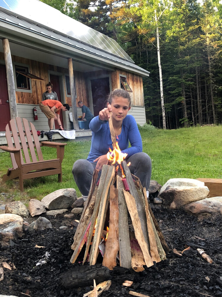 Neveah Burnham, a member of the Carrabec High School outing club, built a campfire during a club trip to Maine Huts & Trails last year. The club won the trip through the Teens to Trails Trip Lottery.