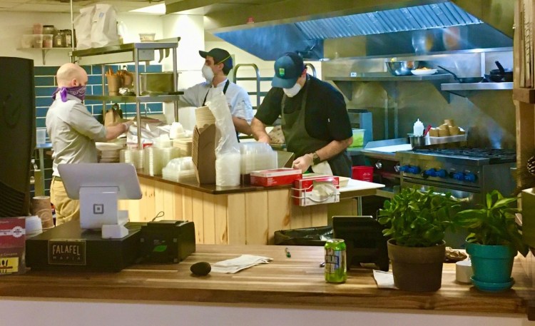 Nura Hummus and Falafel Bar owners Dylan and Cameron Gardner wear masks while making falafel sandwiches after reopening. 