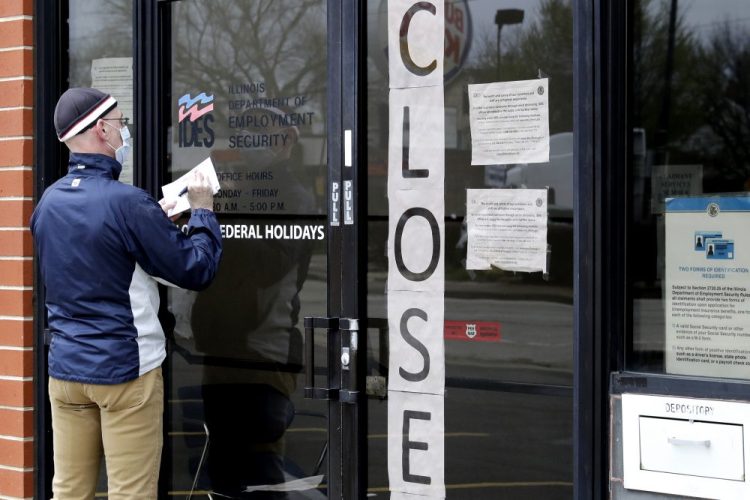 A man writes down information in front of Illinois Department of Employment Security in Chicago on April 30. U.S. businesses cut an unprecedented 20.2 million jobs in April.