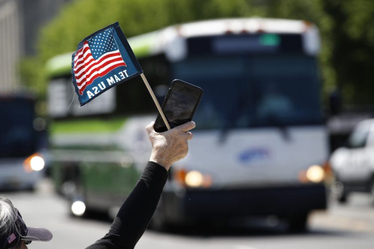 Tour guide Barbara Western waves a flag in support of bus and motor coach operators circling the National Mall in Washington on May 13 for a rally to raise awareness of the industry. America's private buses are ground to a halt, and members of the industry say they need federal assistance to help the country get back to work and play.