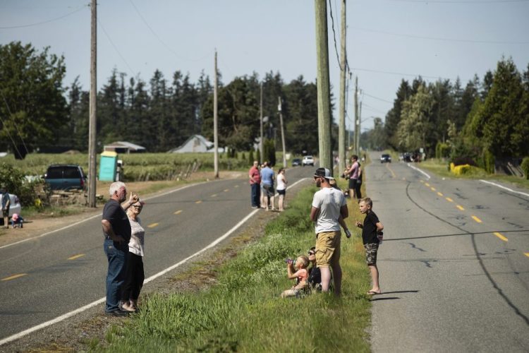 U.S. residents, left, and Canadian residents, right, gather across a ditch along the Canada-U.S. border, in Abbotsford, British Columbia, on May 10. The stretch of international border southeast of Vancouver has become a popular meeting spot for families, loved ones and friends separated due to the closure of the Canada-U.S. border to non-essential travel due to the coronavirus concerns. 