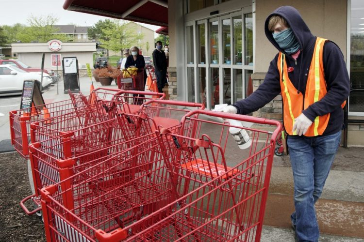 Dilon Moore disinfects shopping carts and controls the number of customers allowed to shop at one time at a Trader Joe's supermarket in Omaha, Neb., on Thursday. Store workers across the country are suddenly being asked to enforce the rules that govern shopping during the coronavirus pandemic.