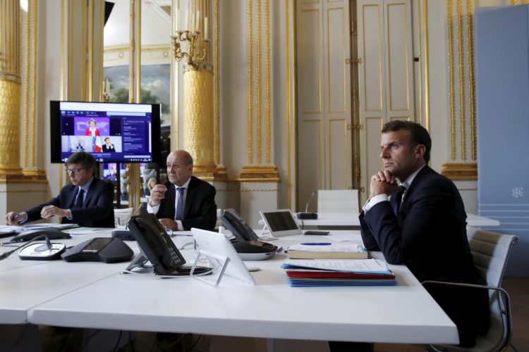 French President Emmanuel Macron listens at the Elysee Palace in Paris as he attends Monday's international videoconference on a COVID-19 vaccine. 
