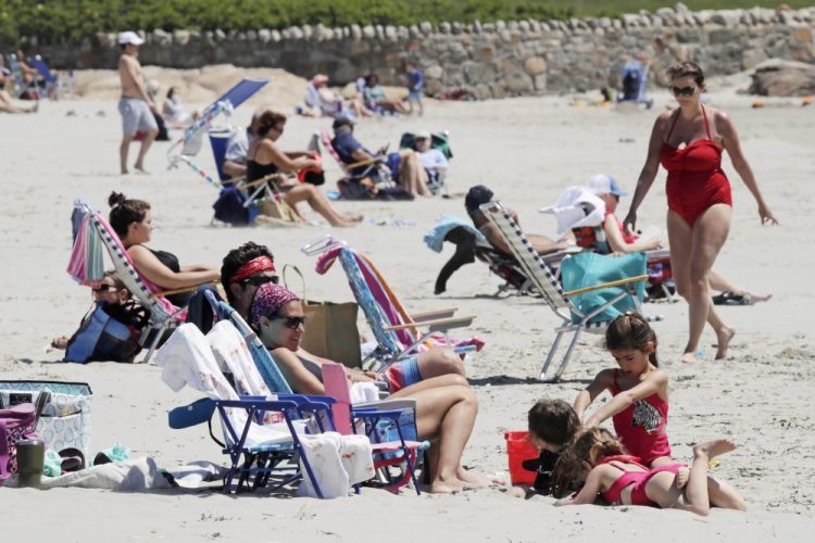 People relax on the shore at Good Harbor Beach in Gloucester, Mass., on Friday. Beaches in Gloucester reopened with restrictions Friday after being closed two months ago because of the pandemic.