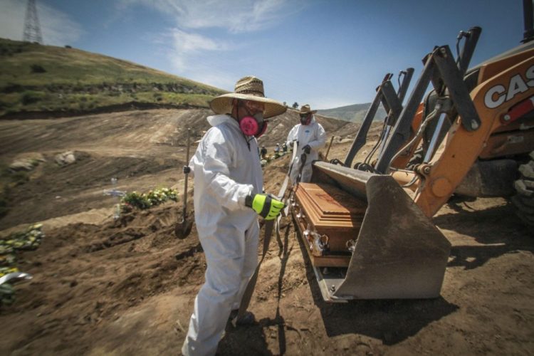 Workers unload a coffin May 5 that contains the remains of a person who died from the new coronavirus, in an area of the municipal cemetery set apart for victims of COVID-19, in Tijuana, Mexico. 