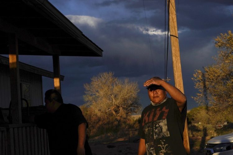 Eugene Dinehdeal shields his face from the setting sun on the Dinehdeal family compound in Tuba City, Ariz., on the Navajo reservation on April 20, 2020. The Navajo reservation has some of the highest rates of coronavirus in the country. If Navajos are susceptible to the virus' spread in part because they are so closely knit, that's also how many believe they will beat it. 