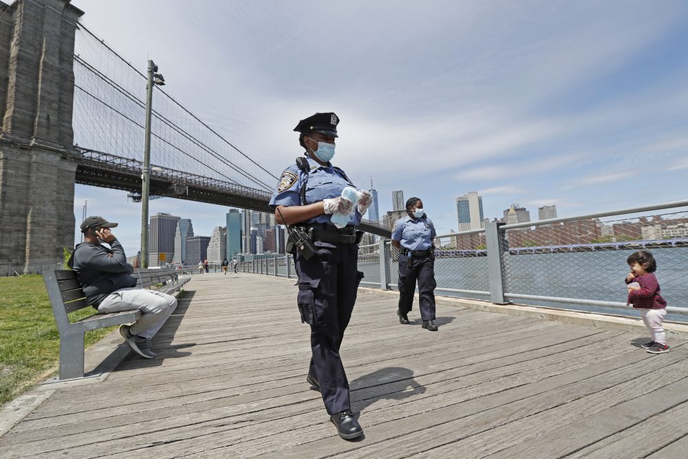 New York City police officers patrol Brooklyn Bridge Park on Sunday and distribute face masks to anyone who needs or asks for one. 