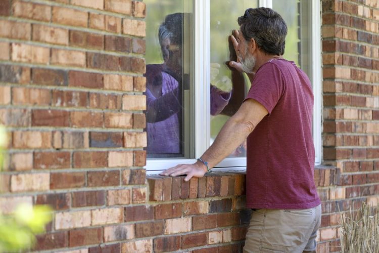 Jack Campise talks with his mother, Beverly Kearns, through her apartment window at the Kimberly Hall North nursing home on Thursday in Windsor, Conn. Nursing home operators say the lack of testing kits and other resources have left them nearly powerless to stop the virus from entering their facilities.