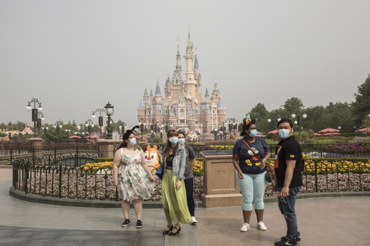 Visitors wearing protective masks stand in front of the Enchanted Storybook Castle during the reopening of the Walt Disney Co. Shanghai Disneyland theme park in Shanghai on May 11.
