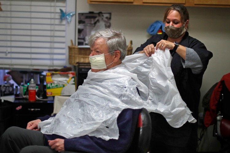 Ann Fouquette uses a trash bag for an apron before cutting Jan Smith's hair at Kilroy's Haircutters on May 1 in Brunswick.