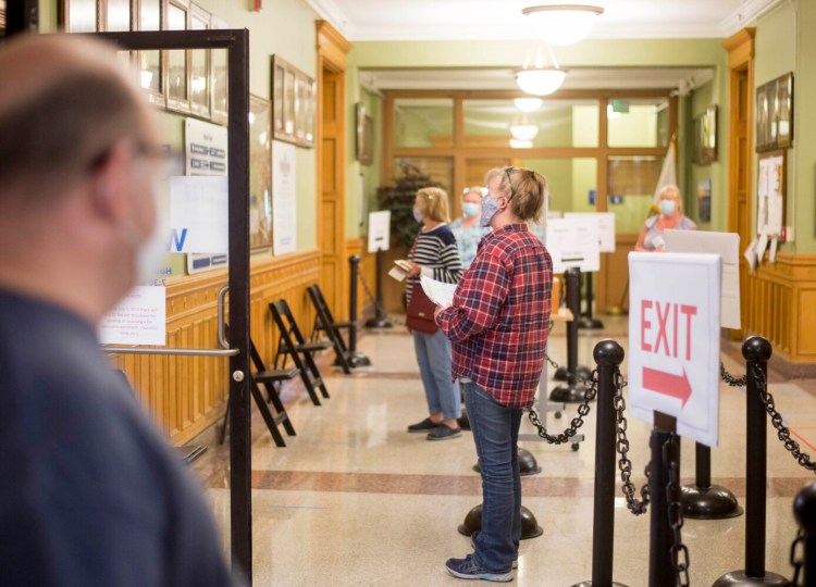 People wearing masks wait at a safe distance Tuesday afternoon inside Waterville City Hall, which has reopened to the public amid the coronavirus pandemic. 