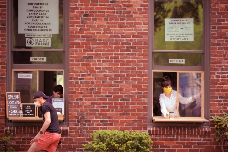 A customer leaves the ordering window while barista Paige Auber puts a coffee out for pickup at Bard Coffee on Middle Street in Portland in early June. The coffee shop installed the ordering and pickup windows because of the pandemic but says they may continue to use them even after the pandemic ends.