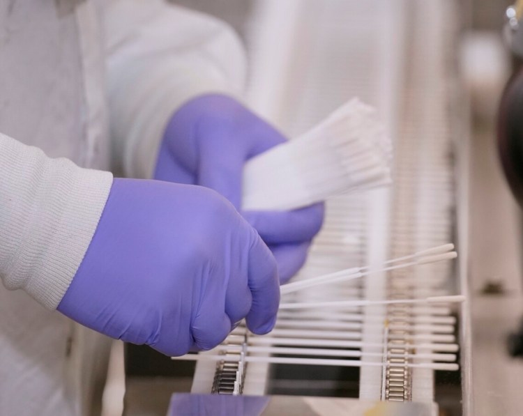 An employee at Puritan Medical Products places swabs on a conveyor in June 2020, shortly after the COVID-19 pandemic was announced.