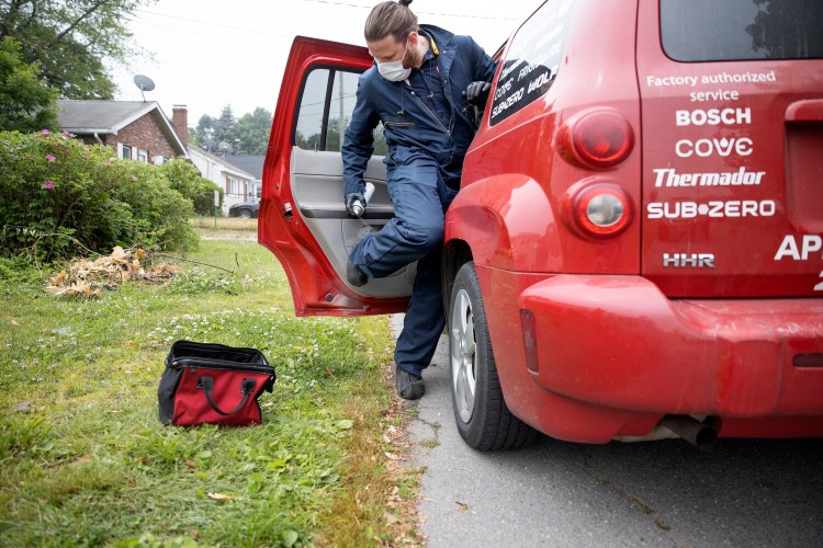 Craig Maloney, an appliance technician for Metropolitan Services, disinfects his boots and clothing after repairing a refrigerator in South Portland last Wednesday. Businesses in Maine that rely on in-home service are either finding ways to adapt to the coronavirus pandemic or staying on the sidelines.