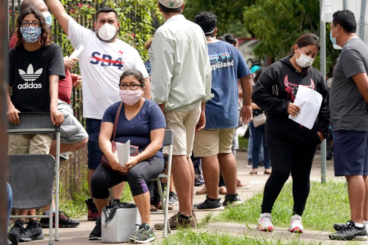 People wait in line at a free COVID-19 testing site provided by United Memorial Medical Center at the Mexican Consulate on Sunday in Houston. Confirmed cases of the coronavirus in Texas continue to surge. Texas Gov. Greg Abbott, on Friday, shut down bars again and scaled back restaurant dining as cases climbed to record levels after the state embarked on one of America's fastest reopenings. 