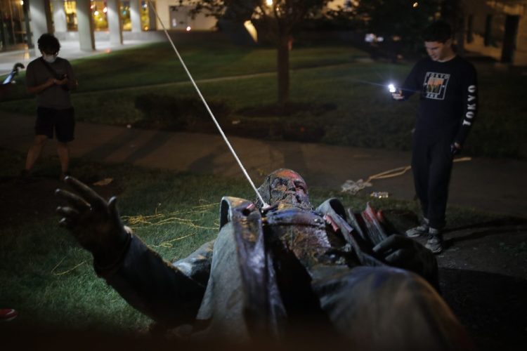 People film the only statue of a Confederate general, Albert Pike, in the nation's capital after it was toppled by protesters and set on fire in Washington early Saturday morning. 