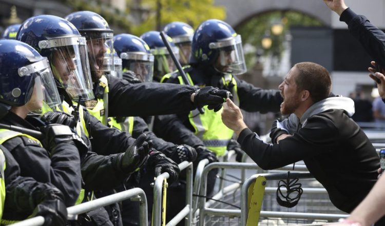 Police are confronted by a protester Saturday in Whitehall near Parliament Square, London, during a protest by the Democratic Football Lads Alliance against a Black Lives Matter protest. The death of George Floyd in the United States has prompted demonstrations by far-right groups as well as the Black Lives Matter movement and provoked a wider debate regarding many historical figures and Britain's colonial past. 