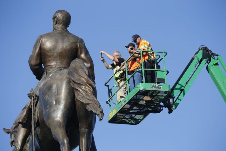 An inspection crew from the Virginia Department of General Services inspects the statue of Confederate Gen. Robert E. Lee on Monday in Richmond, Va. Gov. Ralph Northam has ordered the removal of the statue.