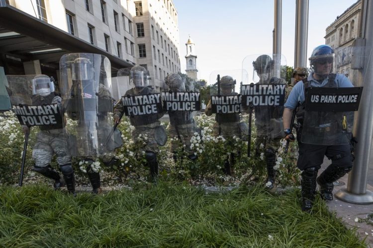 District of Columbia National Guard, and U.S. Park Police, advance through the white roses in front of the AFL-CIO headquarters as they move demonstrators back in Washington. 