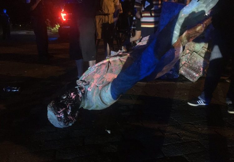 The statue of Confederate President Jefferson Davis is splattered with paint after being toppled Wednesday night in Richmond, Va.