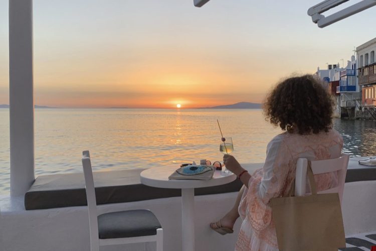 A visitor watches the sunset at a bar in Mykonos, Greece, on June 9. Greece will officially launch its tourism season Monday after keeping the country's infection rate low. 