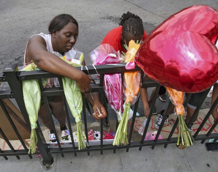 People attend to a memorial at the site of a Wendy's restaurant Sunday in Atlanta. On Saturday, protesters set fire to the Wendy's where Rayshard Brooks, a black man, was shot and killed by Atlanta police Friday evening following a struggle in the drive-thru line. Steve Schaefer/Atlanta Journal-Constitution via AP