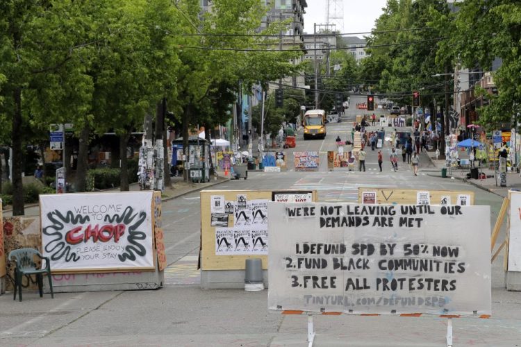 A sign on the street welcomes visitors and a list of demands is posted Wednesday, inside the CHOP (Capitol Hill Occupied Protest) zone in Seattle. (AP Photo/Ted S. Warren)