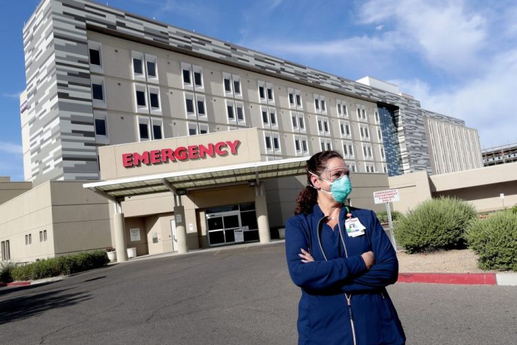 Caroline Maloney stands outside HonorHealth's Scottsdale Osborn Medical Center at the end of her overnight shift early Friday in Scottsdale, Ariz. The state is one of the world's COVID-19 hot spots.  