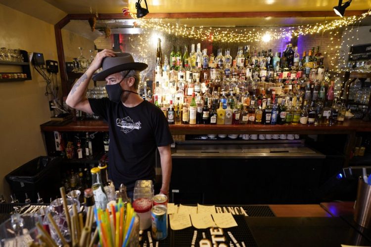 Michael Neff, co-owner of the Cottonmouth Club, adjusts his hat as he stands behind the bar Tuesday in Houston. Neff closed his downtown bar because of concerns within the industry as the number COVID-19 case continues to rise in Houston.