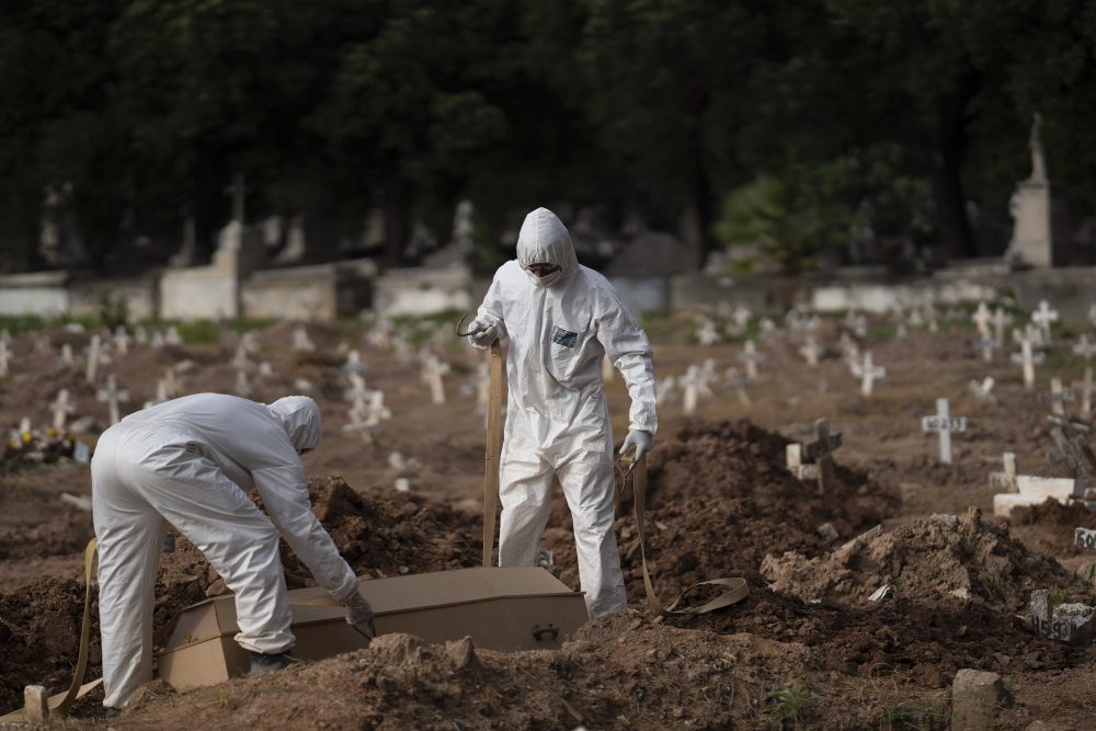 Cemetery workers in protective clothing maneuver the coffin of 57-year-old Paulo Jose da Silva, who died from the new coronavirus, in Rio de Janeiro on Friday. Brazil has nearly 700,000 cases, second in the world, according to Johns Hopkins University.
