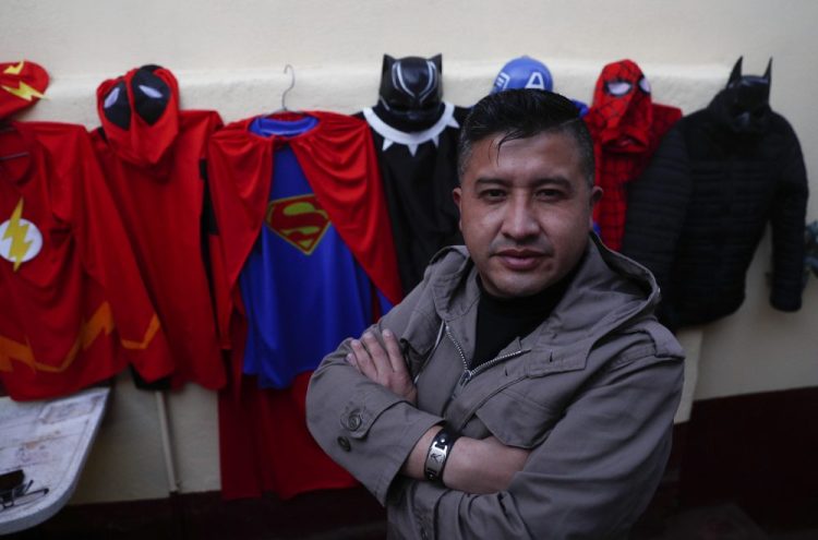 Art teacher Jorge Manolo Villarroel poses for a photo next to his superhero costumes, after imparting one of his online classes Tuesday from his home, amid the new coronavirus pandemic in La Paz, Bolivia. Villarroel makes the costumes he wears. "I had to improvise since with the quarantine I couldn't get out," he said.
