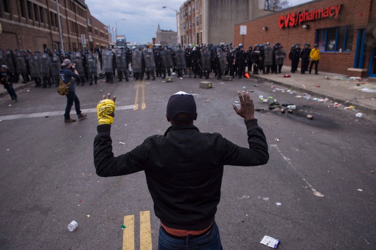 People stand with their hands up as officers move toward them during a protest for Freddie Gray in Baltimore on April 27, 2015. 