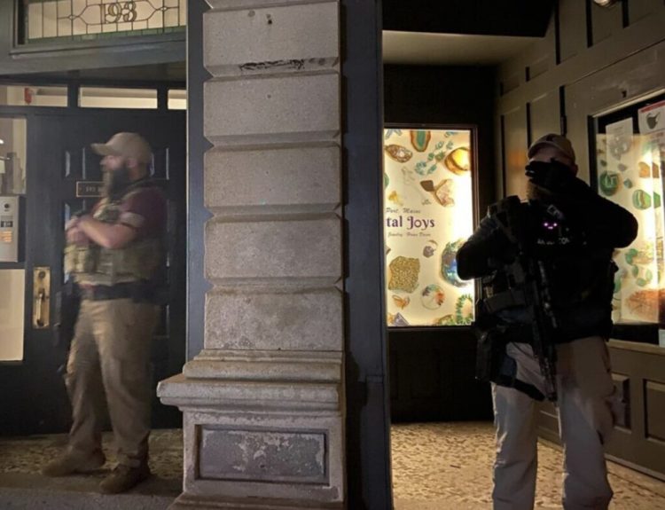 Two unidentified armed men stand guard outside an Old Port building during an anti-racism demonstration Tuesday.