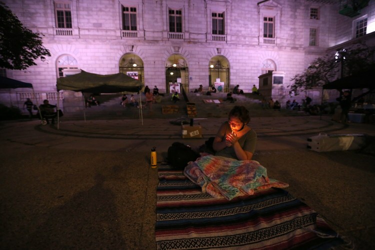 Christan Sark, 19, who is homeless and pregnant, lights a cigarette while sitting on a blanket outside Portland City Hall, where she intended to sleep Wednesday night.