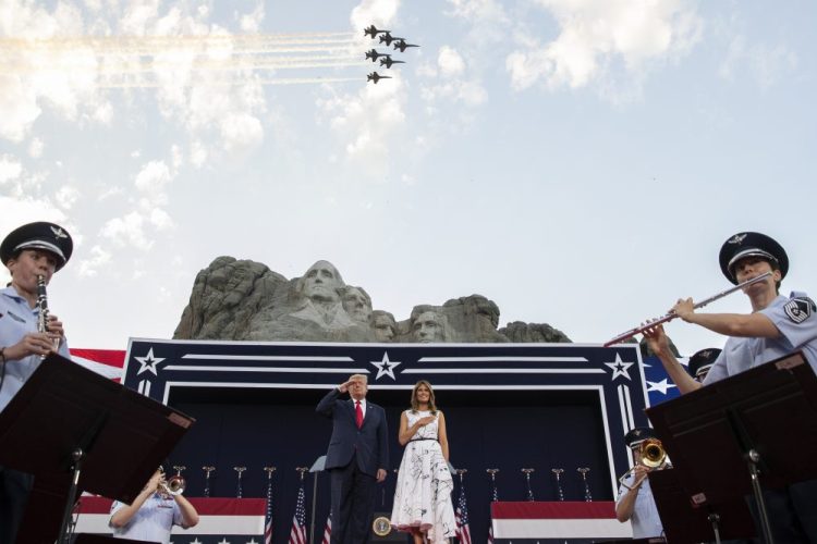 President Trump, accompanied by first lady Melania Trump, stands during the national anthem with a flyover by the U.S. Navy Blue Angles at Mount Rushmore National Memorial on Friday near Keystone, S.D.