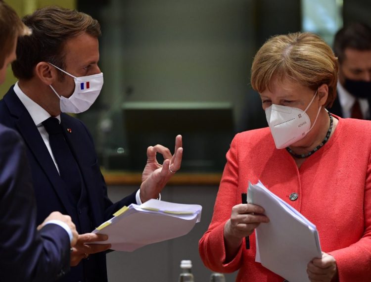 German Chancellor Angela Merkel, right, and French President Emmanuel Macron during a round table meeting in Brussels on Monday. The 27-country bloc finally struck a deal on a relief package after a marathon four-day summit. One prime minister called the stimulus deal a "national success."