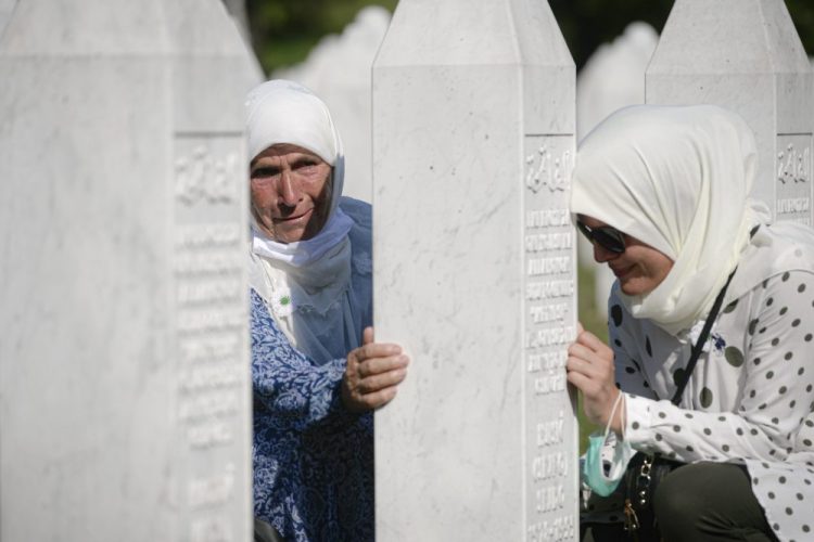 Women lean on a gravestone in Potocari, near Srebrenica, Bosnia, on Saturday.