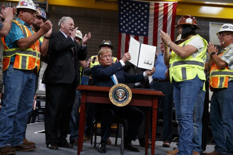 President Trump holds up an executive order on energy and infrastructure after signing it at the International Union of Operating Engineers International Training and Education Center in Crosby, Texas, in 2019. Attorneys general in 20 states and the District of Columbia sued the Trump administration on Tuesday, alleging that new federal rules undermine their ability to protect rivers, lakes and streams within their borders. 