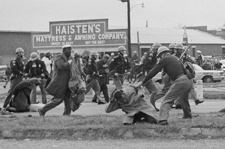 Astate trooper swings a billy club at John Lewis, right foreground, chairman of the Student Nonviolent Coordinating Committee, to break up a civil rights voting march in Selma, Alabama, in 1965. Lewis sustained a fractured skull. Lewis, who carried the struggle against racial discrimination from Southern battlegrounds of the 1960s to the halls of Congress, died Friday. 