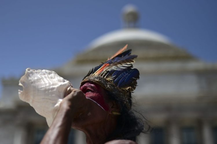 Baracutey blows on a conch shell outside the Capitol building while joining a group of activists demanding statues and street names commemorating symbols of colonial oppression be removed, in San Juan, Puerto Rico on Saturday.
