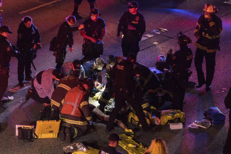 Emergency workers tend to an injured person on the ground after a driver sped through a protest-related closure on the Interstate 5 freeway in Seattle, authorities said early Saturday. Dawit Kelete, 27, has been arrested and booked on two counts of vehicular assault.