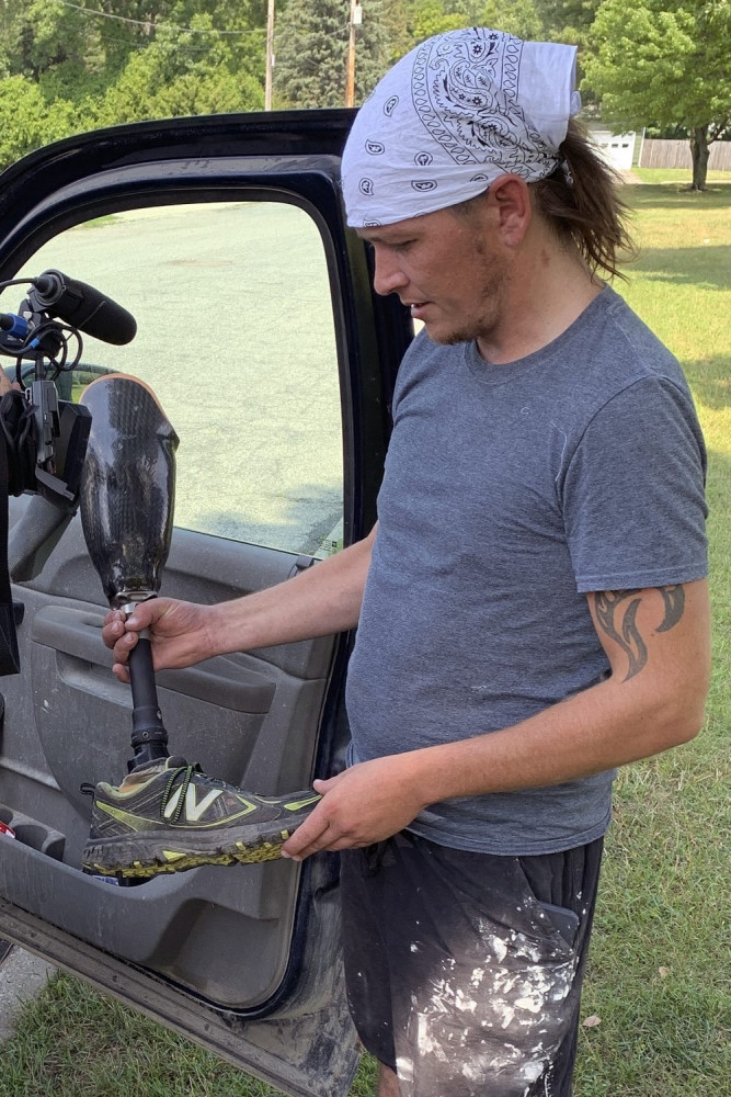 Joe Marszalkowski holds a prosthetic leg on  Monday that he found Sunday in a soybean field on his farm in West Addison, Vt. The leg was lost by double amputee Chris Marckres while skydiving on Saturday. 