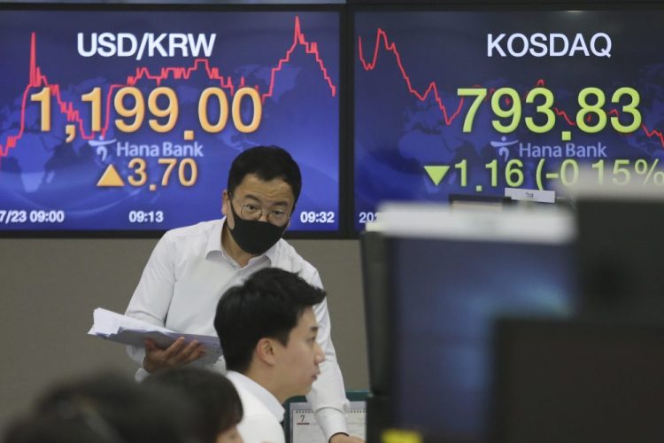 A currency trader talks with his colleague at the foreign exchange dealing room of the KEB Hana Bank headquarters Thursday in Seoul, South Korea. Shares were mixed in Asia on Thursday, with the region’s biggest market in Tokyo closed for a four-day weekend.