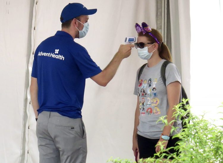 A person gets her temperature taken before entering the official reopening day of the Magic Kingdom at Walt Disney World on Saturday. 