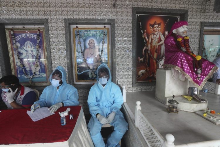 Health workers wait to screen people for COVID-19 symptoms at a temple in Mumbai, India, on Saturday,. India passed 1 million coronavirus cases on Friday, third only to the United States and Brazil.
